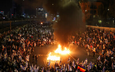 Fire burns as people attend a demonstration after Israeli Prime Minister Benjamin Netanyahu dismissed the defense minister and his nationalist coalition government presses on with its judicial overhaul, in Tel Aviv, Israel, March 27, 2023. REUTERS/Nir Elias