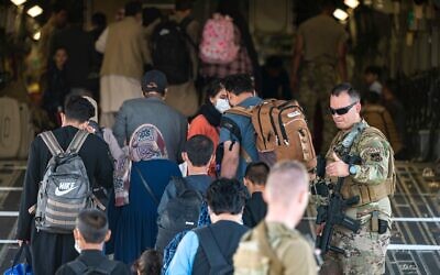 2GFB2H1 U.S. Air Force Airmen guides qualified evacuees aboard a U.S. Air Force C-17 Globemaster III in support of the noncombatant evacuation operation at Hamid Karzai International Airport (HKIA), Afghanistan, Aug. 24, 2021. The Department of Defense is committed to supporting the U.S. State Department in the departure of U.S. and allied civilian personnel from Afghanistan and to evacuate Afghan allies to safety. (U.S. Air Force photo by Senior Airman Taylor Crul)