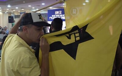 A far right-wing activist kisses the flag of the outlawed Kach movement, a hard line Israeli militant group that advocates for the expulsion of Arabs from the biblical lands of Israel during a ceremony honouring late Jewish extremist leader Rabbi Meir Kahane.