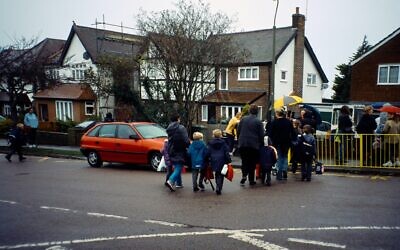 File image of parents crossing the road to take their children to school