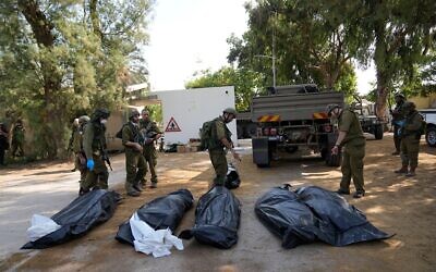 Israeli soldiers stand next to the bodies of Israelis killed by Hamas terrorists in kibbutz Kfar Aza