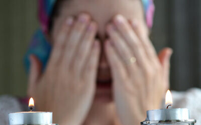 Jewish woman says the blessing upon lighting the sabbath candles before shabbat eve dinner.