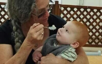 In this touching photograph, Maya, with her long grey hair tied in a braid, lovingly feeds baby Kfir, who gazes up at her with wide, innocent eyes.